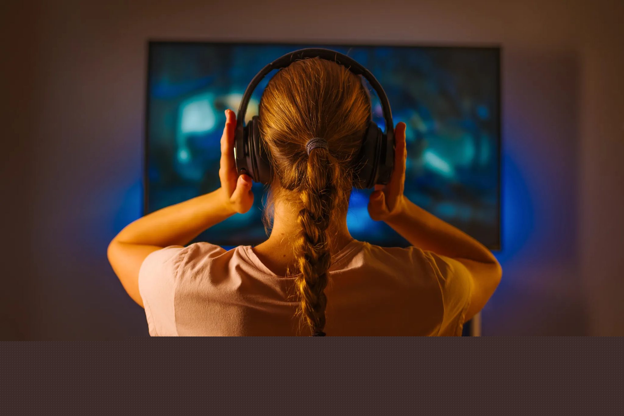 Mladá žena, která sleduje televizi se sluchátky
