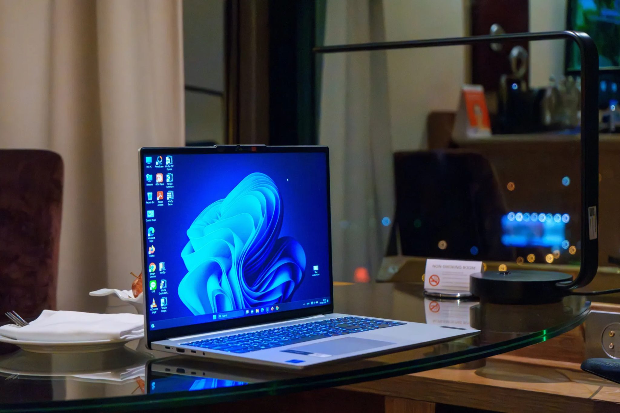 Windows -laptop na skleněném stole s ikonami na ploše
