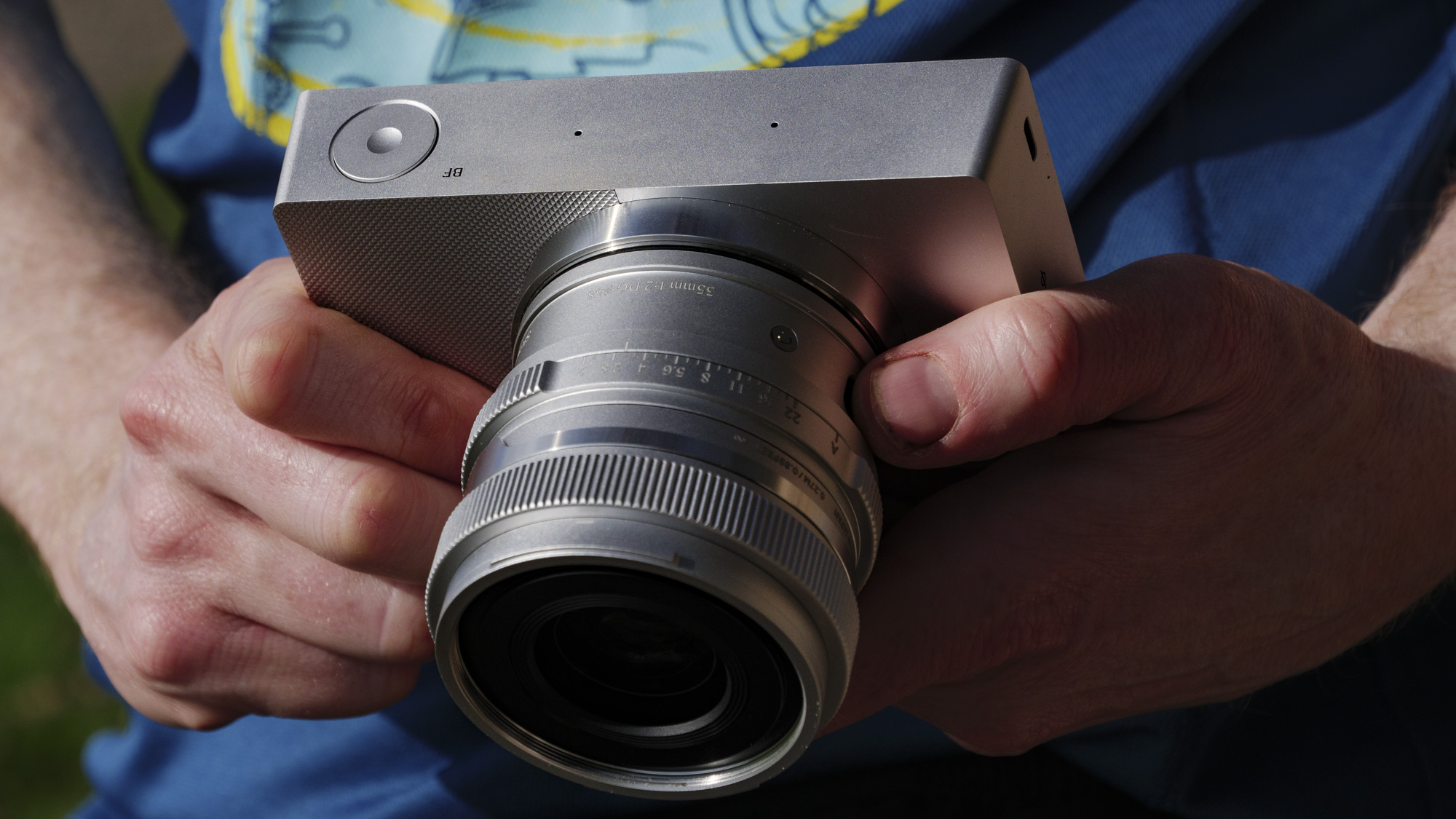 Stříbrná kamera Sigma BF s 35 mm f/2 dg čočkou připojená v ruce