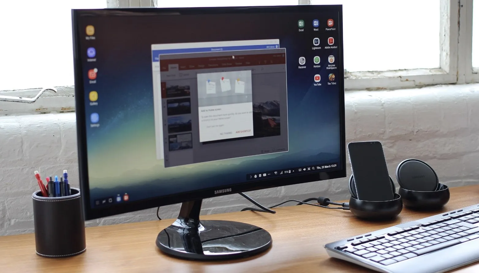 Obrazovka Samsung v kanceláři s klávesnicí a zvukovým systémem